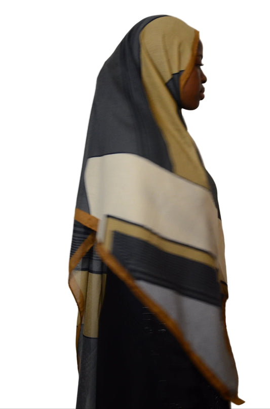 Model wearing an architectural panel modal hijab in charcoal, cream, and gold tones, shown in side profile
