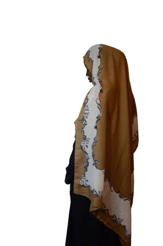 Model wearing a beige brown cotton voile linen hijab with ivory ornate border in a soft side profile drape.