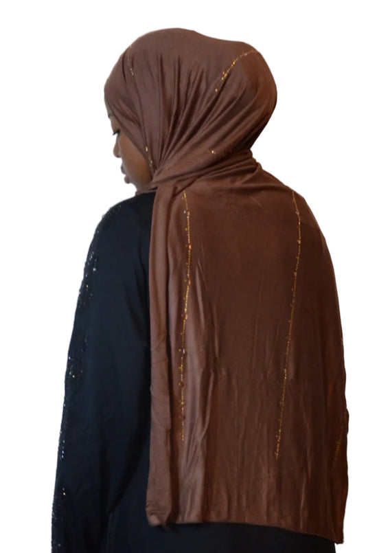 Model wearing a chocolate brown plain jersey hijab with subtle gold bead detailing, styled in a soft front drape.