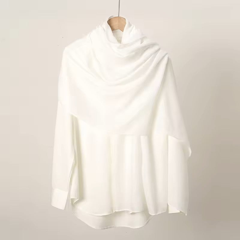 White blouse on a wooden hanger against a plain background