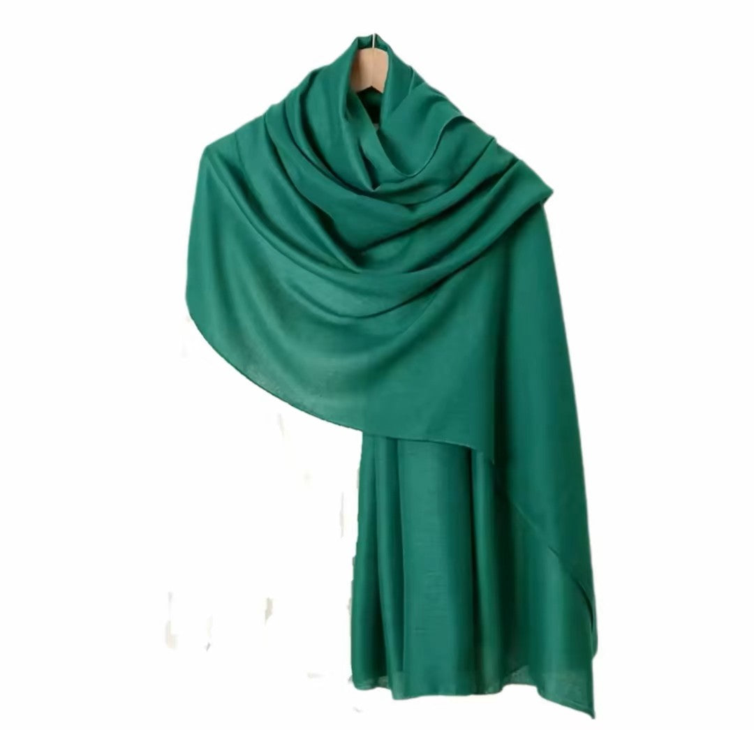 Green scarf draped over a wooden hanger on a white background
