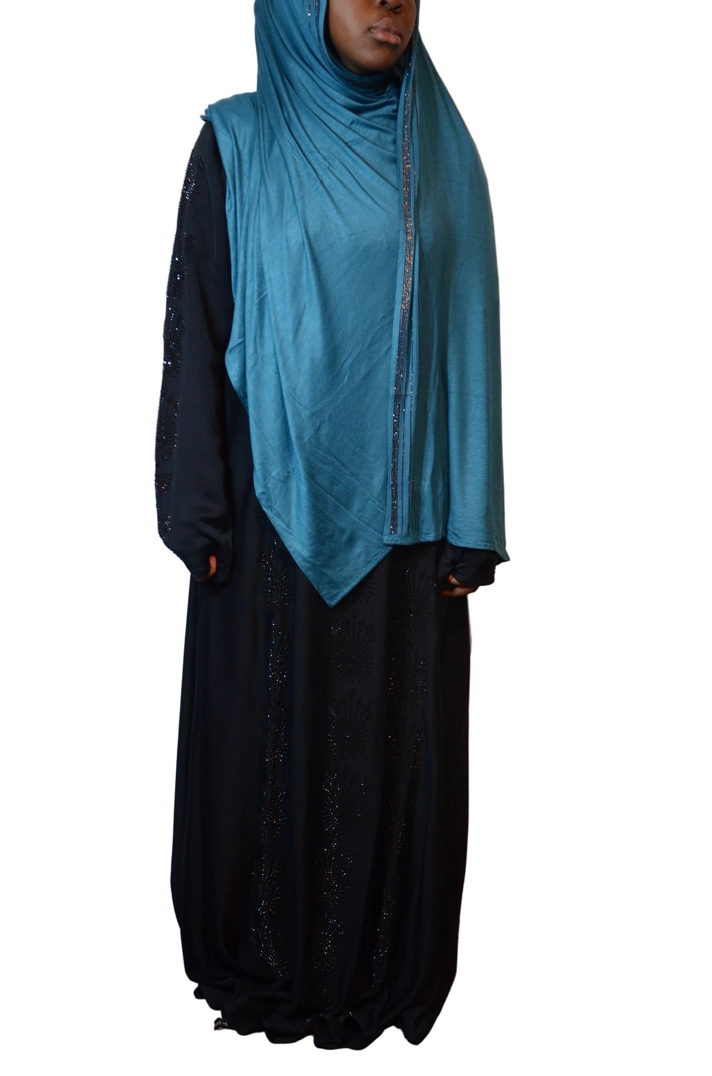 “Model wearing a premium teal cotton jersey hijab with subtle rhinestone edge detailing, styled over a black abaya.”