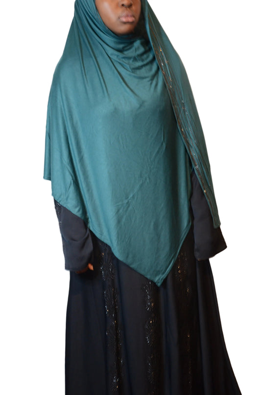 Model wearing a deep teal premium cotton jersey hijab with rhinestone trim, styled in a front draped silhouette.