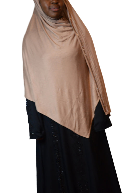 Model wearing a premium jersey hijab with subtle rhinestone trim, softly draped over shoulders for full modest coverage.