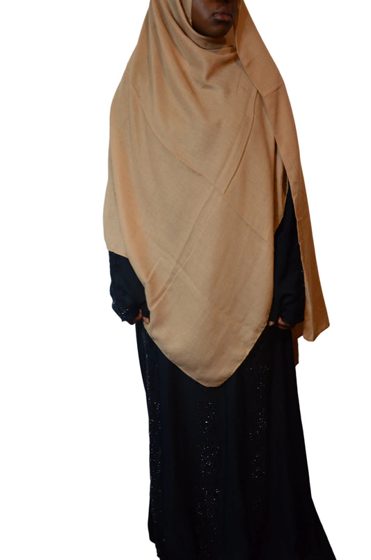 Model wearing a soft sand beige cotton modal hijab styled with a black abaya, showing a lightweight drape and modest coverage.